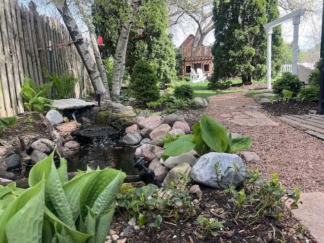 view of yard featuring fence and a garden pond