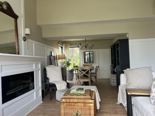 living area with light wood-style floors, a fireplace, a decorative wall, and a chandelier