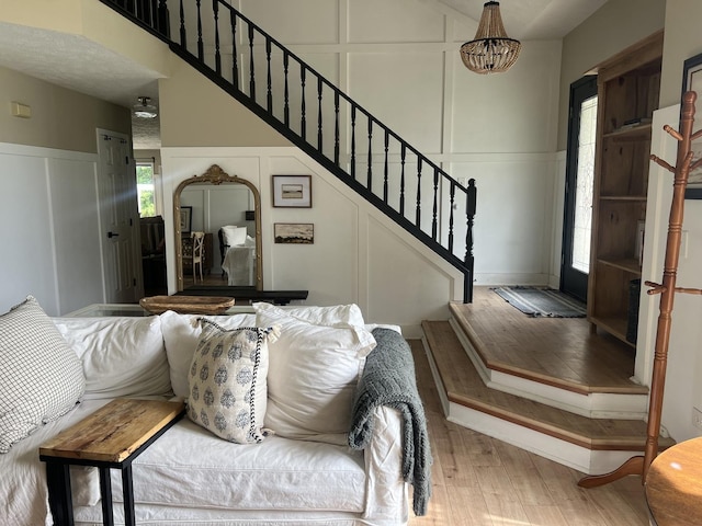 interior space with a wainscoted wall, a decorative wall, stairs, and wood finished floors