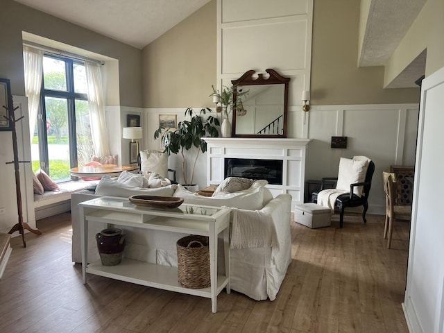 living room featuring vaulted ceiling, a wainscoted wall, hardwood / wood-style flooring, and a decorative wall