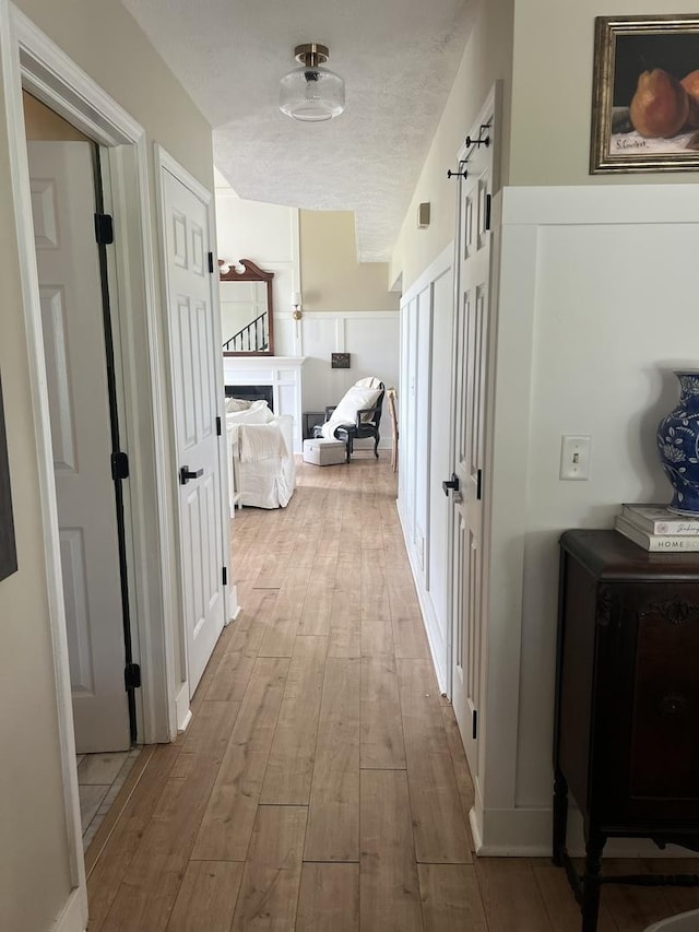 hall with wood-type flooring and a textured ceiling
