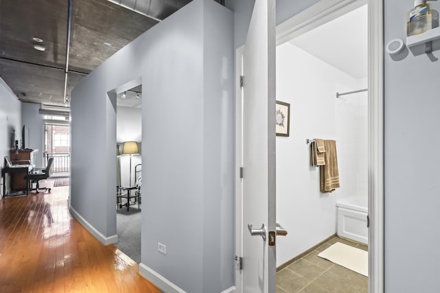 hallway featuring baseboards and wood-type flooring