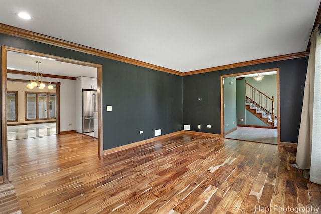 unfurnished room with baseboards, stairs, wood finished floors, and a notable chandelier