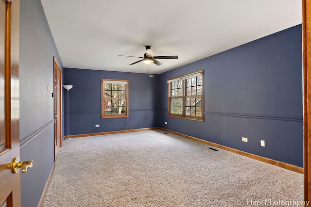 unfurnished room with baseboards, a ceiling fan, carpet, and visible vents