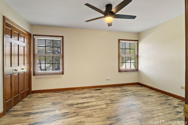 unfurnished bedroom featuring baseboards, a ceiling fan, a closet, and wood finished floors