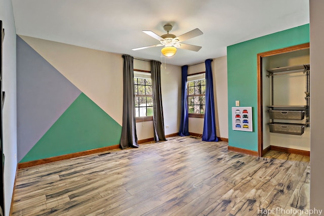 empty room featuring baseboards, a ceiling fan, and wood finished floors