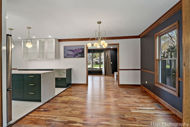 unfurnished dining area featuring wood-type flooring, baseboards, and crown molding