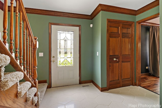 foyer with visible vents, crown molding, light tile patterned floors, baseboards, and stairway