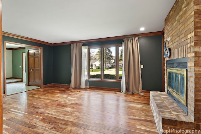 unfurnished living room with crown molding, baseboards, a fireplace, and light wood-type flooring