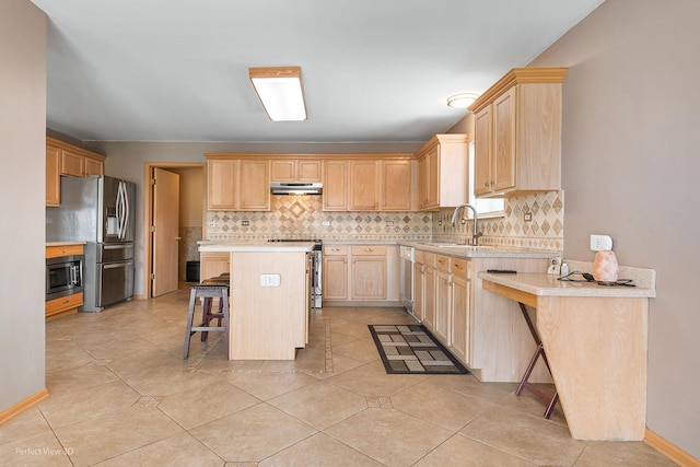 kitchen featuring under cabinet range hood, stainless steel appliances, light brown cabinetry, and a sink