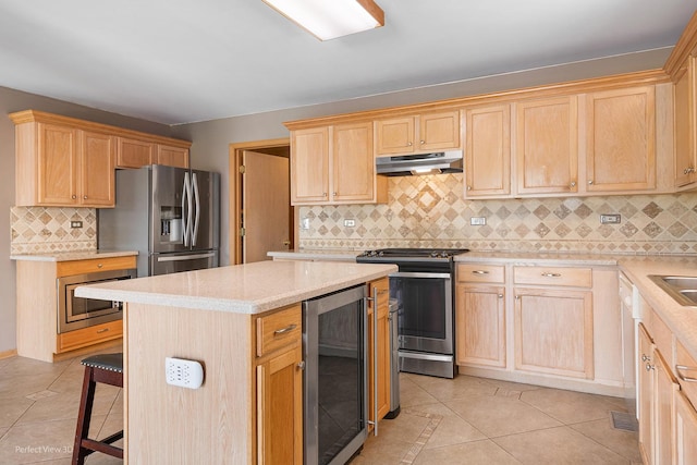 kitchen featuring wine cooler, light brown cabinetry, under cabinet range hood, appliances with stainless steel finishes, and light tile patterned floors