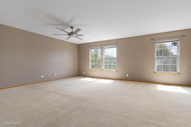 carpeted empty room with baseboards and a ceiling fan
