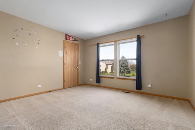 spare room with baseboards, visible vents, and light carpet