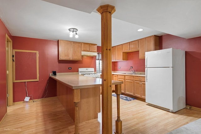 kitchen with a sink, light wood-style floors, white appliances, light countertops, and under cabinet range hood