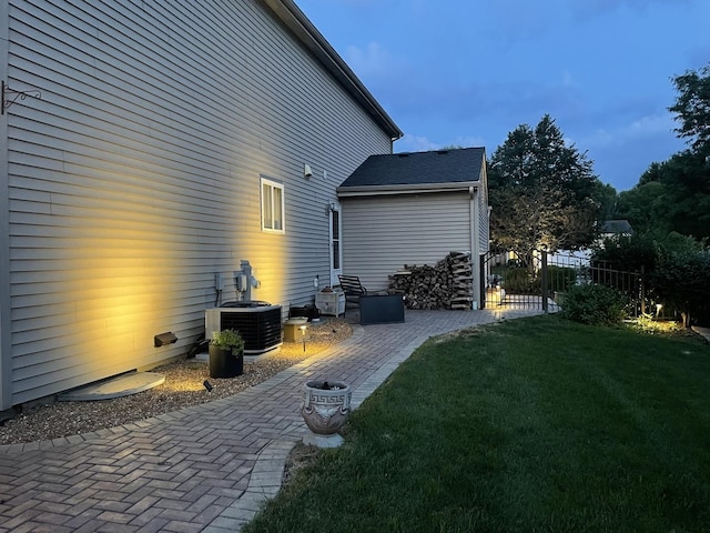 rear view of property with fence, central AC unit, a yard, and a patio