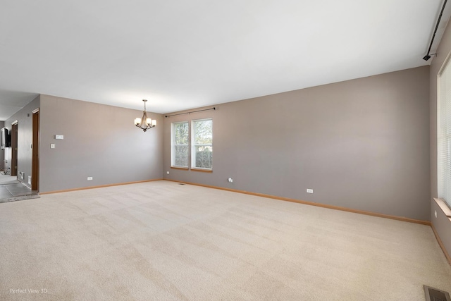 carpeted empty room with a notable chandelier, visible vents, and baseboards