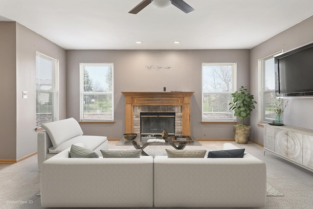 living room featuring a ceiling fan, baseboards, a fireplace, and carpet flooring
