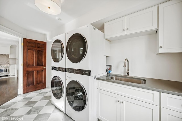 laundry area featuring a sink, cabinet space, stacked washing maching and dryer, and washing machine and clothes dryer