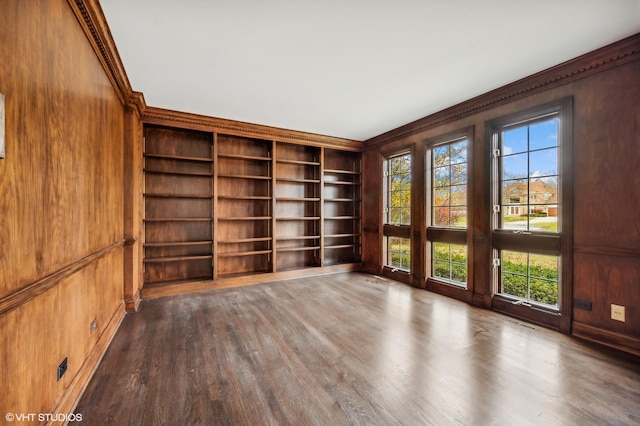 unfurnished room with ornamental molding, wood walls, dark wood-style floors, and built in features