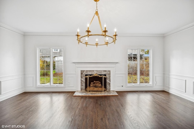 unfurnished living room featuring a notable chandelier, wainscoting, and wood finished floors