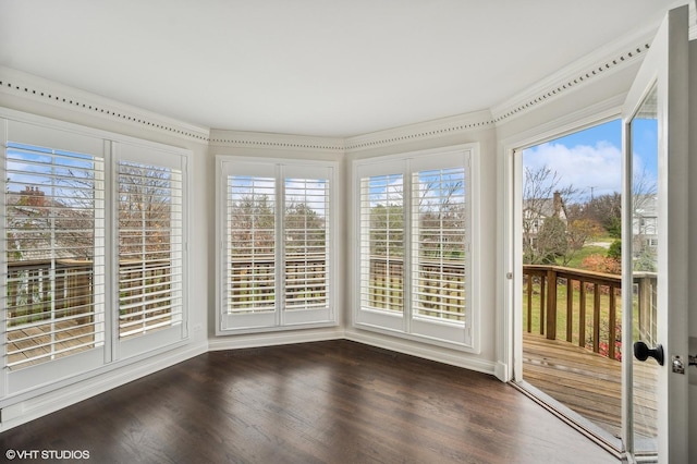 unfurnished sunroom featuring baseboards, a wooden deck, and wood finished floors