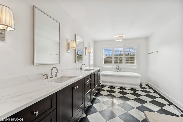 full bathroom with a sink, a freestanding tub, tile patterned floors, and double vanity