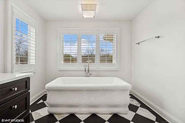 bathroom with a freestanding tub, baseboards, and vanity
