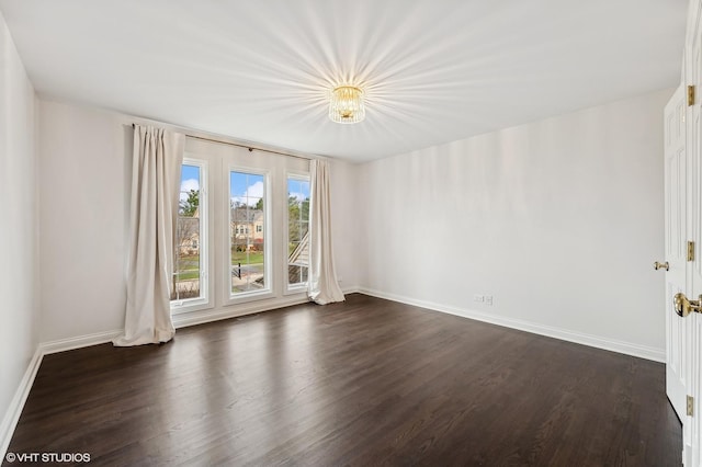 unfurnished room featuring baseboards and dark wood finished floors