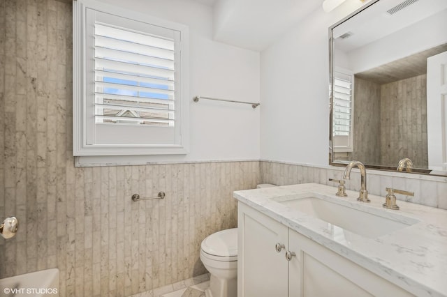 bathroom with vanity, wainscoting, toilet, and visible vents