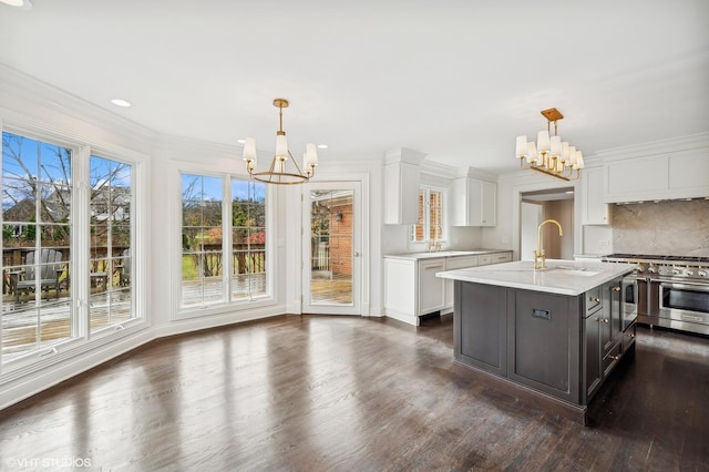 kitchen with an inviting chandelier, light countertops, white cabinetry, dark wood finished floors, and double oven range