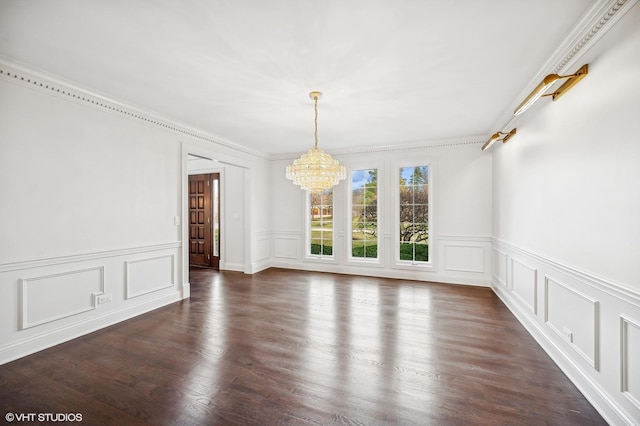 unfurnished dining area with an inviting chandelier, ornamental molding, dark wood-style flooring, wainscoting, and a decorative wall