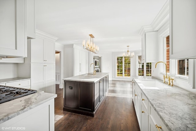kitchen featuring a sink, dark wood-style flooring, a notable chandelier, and white cabinets