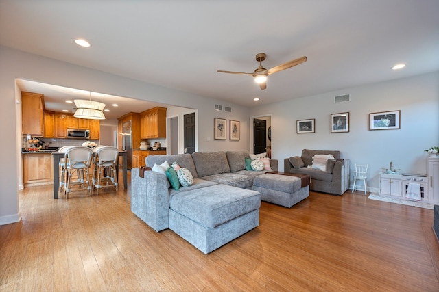 living room featuring recessed lighting, light wood-style flooring, and visible vents