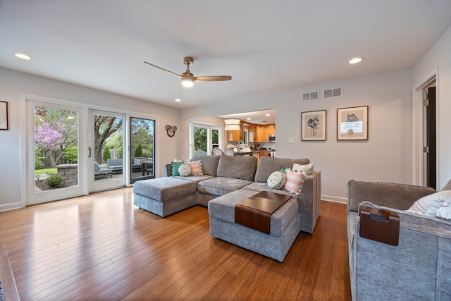 living room featuring baseboards, ceiling fan, visible vents, and wood finished floors