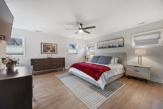 bedroom with a ceiling fan, baseboards, visible vents, and light wood-style flooring
