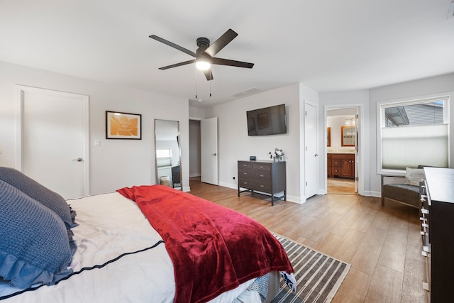 bedroom featuring baseboards, visible vents, light wood-style flooring, and ensuite bathroom