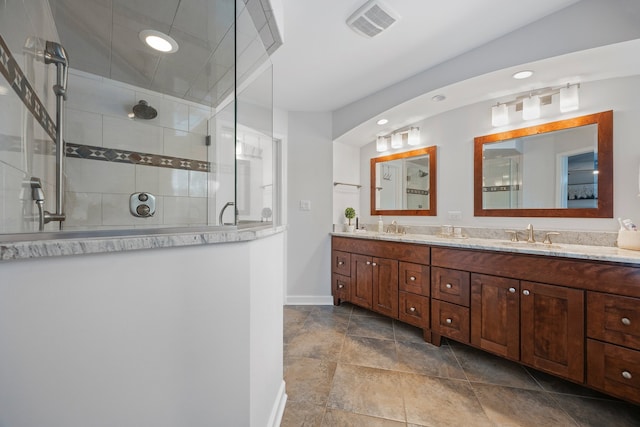 bathroom with visible vents, double vanity, baseboards, a sink, and a tile shower