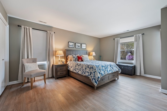 bedroom featuring visible vents, baseboards, and wood finished floors