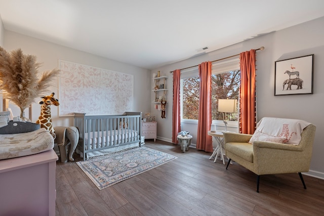 bedroom featuring baseboards, wood finished floors, and visible vents