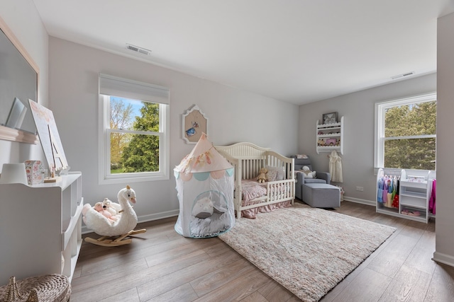 bedroom featuring visible vents, multiple windows, and hardwood / wood-style floors