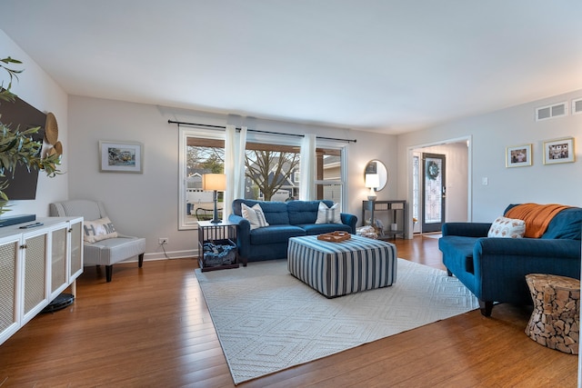living room featuring baseboards, visible vents, and wood finished floors