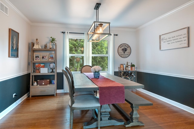 dining space with baseboards, ornamental molding, wood finished floors, and visible vents