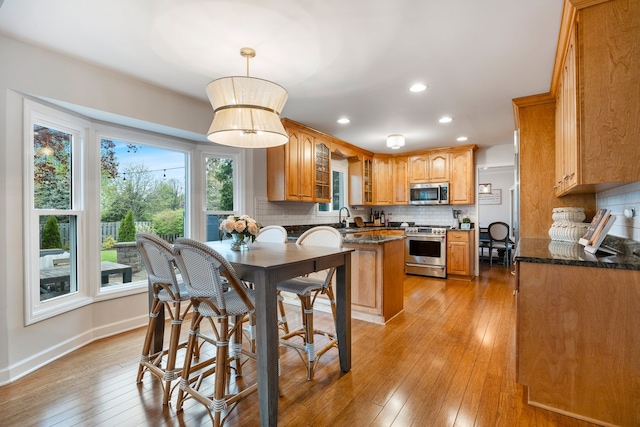 kitchen featuring appliances with stainless steel finishes, tasteful backsplash, a sink, recessed lighting, and light wood-style flooring