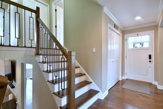 foyer with visible vents, ornamental molding, wood finished floors, baseboards, and stairway