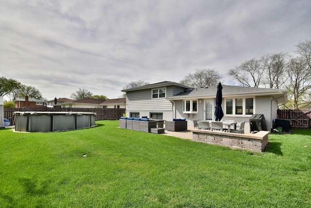 rear view of property with a yard, an outdoor living space, a fenced backyard, and a fenced in pool