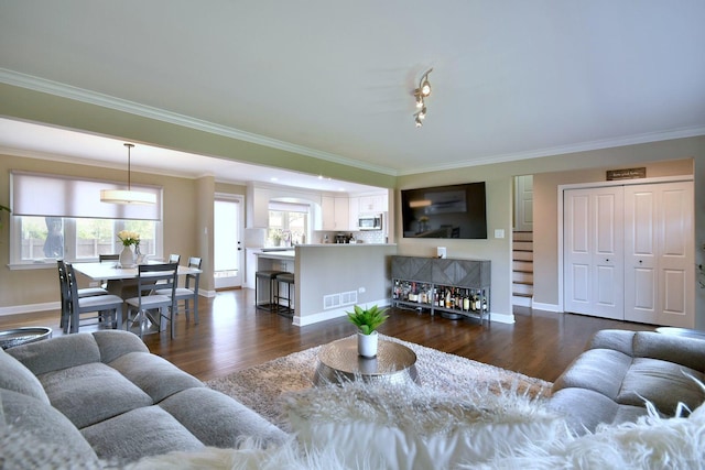 living area featuring baseboards, ornamental molding, and visible vents