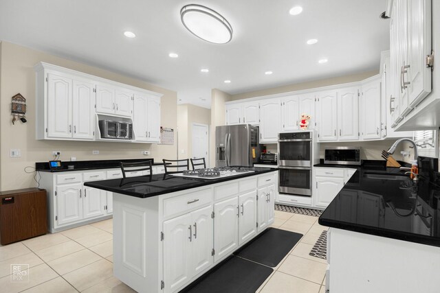 401 Jason Ln, Schaumburg, IL 60173 - kitchen with a kitchen island, a sink, light tile patterned floors, stainless steel appliances, and white cabinetry