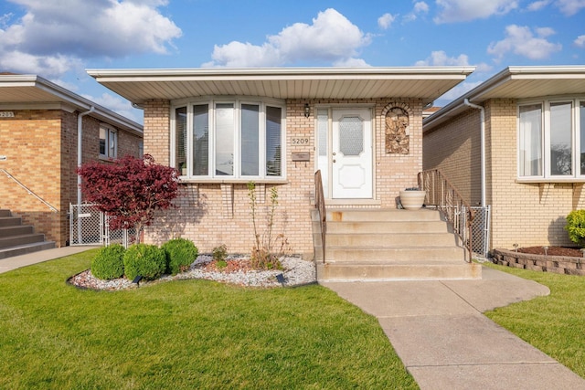entrance to property featuring a yard and brick siding
