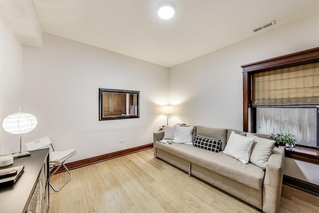 living room featuring baseboards, light wood finished floors, and visible vents