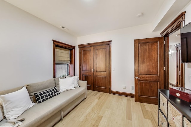 living room featuring light wood-style floors, baseboards, and visible vents